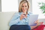 Smiling woman drinking wine and using a tablet pc