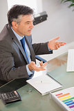 A businessman sitting at his desk explaining something