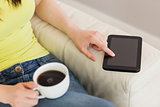 Girl using a tablet pc and holding a cup of coffee