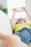 Smiling teen lying on a sofa using a tablet pc