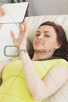 Happy teen girl lying on a sofa using a tablet pc