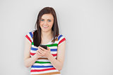 Smiling girl using her mobile phone looking at camera