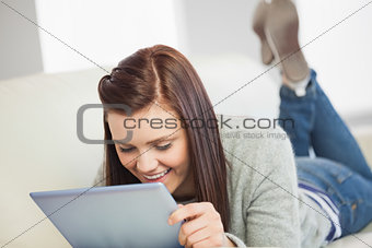 Relaxed girl looking and using a tablet pc on a sofa