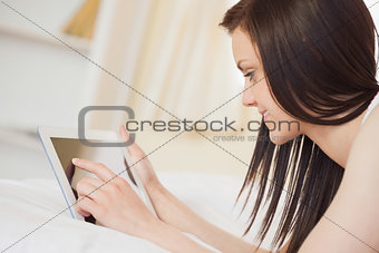 Pretty girl using a tablet pc lying on her bed