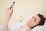 Happy girl listening music on her smartphone lying on bed