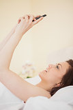 Happy girl using a mobile phone lying on a bed