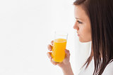 Thoughtful girl holding a glass of orange juice and looking away