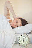 Girl waking in her bed with an alarm clock on foreground
