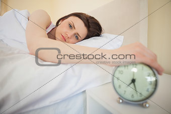 Sleepy girl turning off her alarm clock