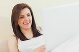 Laughing girl looking and using a laptop lying on a bed