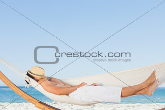 Man wearing straw hat relaxing in a hammock