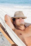 Man wearing straw hat lying in hammock