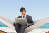 Businessman typing on his laptop in a hammock