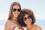 Two friends wearing sunglasses smiling at camera