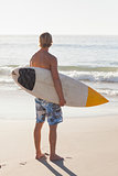 Man with his surfboard on the beach