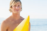 Handsome man with his surfboard smiling at camera