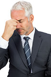 Upset businessman closing his eyes and holding his head