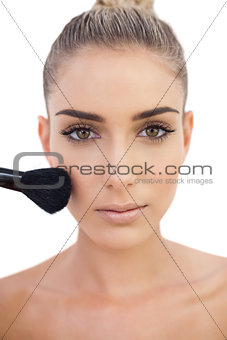 Concentrated woman applying powder on her cheeks