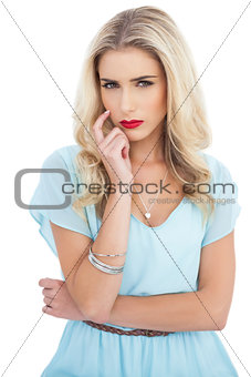 Pensive blonde model in blue dress looking at camera
