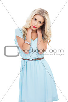 Attractive blonde model in blue dress posing with hands on the hair