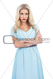 Thoughtful blonde model in blue dress posing crossed arms