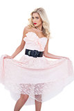 Lovely blonde model in pink dress holding her dress