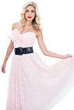 Stylish blonde model in pink dress posing holding her dress
