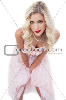 Pretty blonde model in pink dress posing hands on the thighs