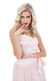 Amused blonde model in pink dress posing a finger on the mouth