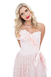 Content blonde model in pink dress posing looking away