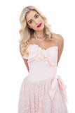 Content blonde model in pink dress posing looking at camera