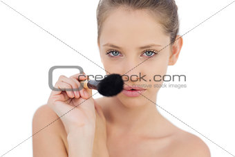 Concentrated brunette model pointing a brush at camera