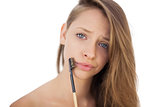 Puzzled brunette model holding a brush