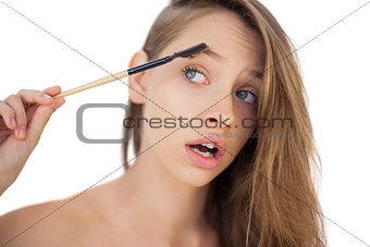 Puzzled brunette model brushing her eyebrows