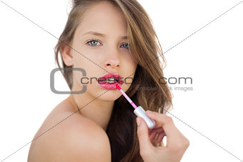 Focused brunette model applying gloss on her lips