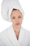 Thinking brunette in bathrobe looking at camera
