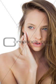 Cute brunette model rubbing her cheeks with cream