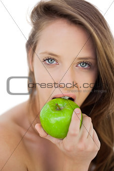 Unsmiling brunette model eating an apple