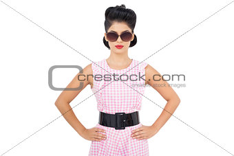 Unsmiling black hair model wearing glasses and posing hands on the hips