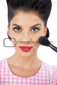 Gorgeous black hair model applying powder on her cheek