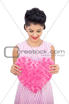 Pleased black hair model holding a pink heart shaped pillow