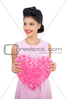 Joyful black hair model holding a pink heart shaped pillow
