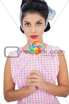 Serious black hair model holding a colored lollipop
