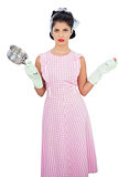 Disppointed black hair model holding a pan and wearing rubber gloves