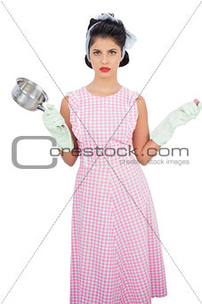 Disppointed black hair model holding a pan and wearing rubber gloves