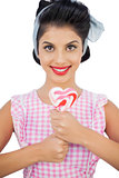 Cheerful black hair model holding a heart shaped lollipop
