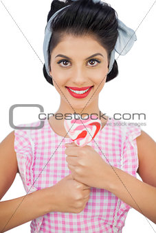 Cheerful black hair model holding a heart shaped lollipop