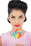 Unsmiling black hair model holding a colored lollipop
