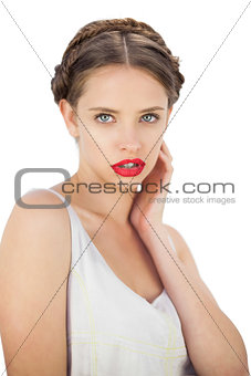 Pensive model in white dress posing with a hand on her cheek