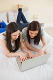 Friends using a laptop lying on bed